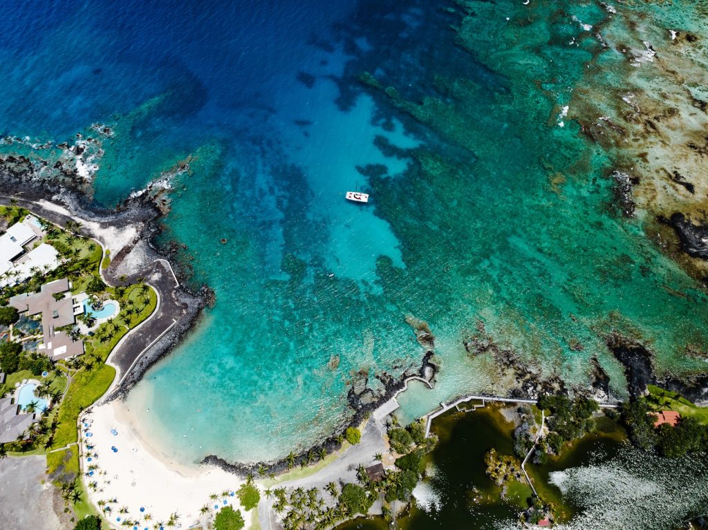 an aerial view of a beach with a boat in the water