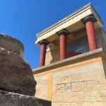 a stone building with two red pillars and a painting on the wall